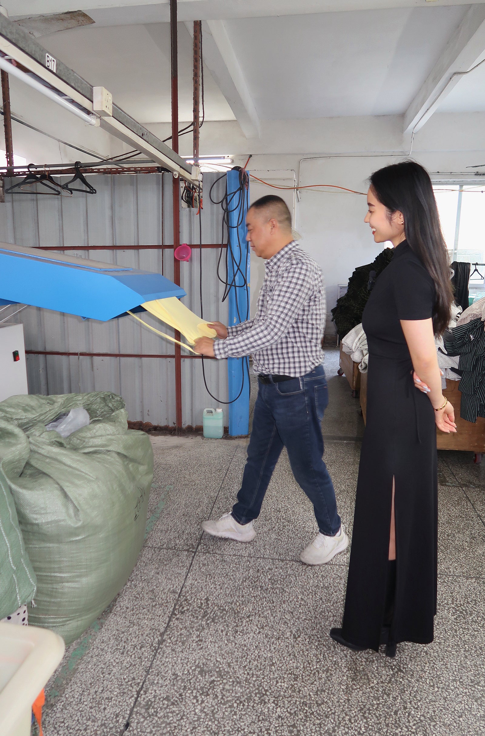 Founder smiling looking at the machine that helps to remove extra threads from the clothes